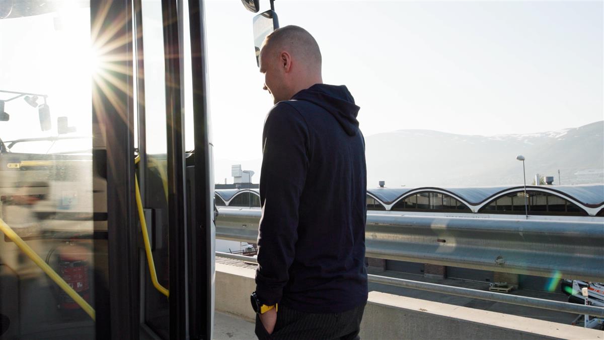 Fotografi av regissør Einar Killie Angelsen går om bord i bussen. Sola skinner gjennom bussvinduet.  - Klikk for stort bilde