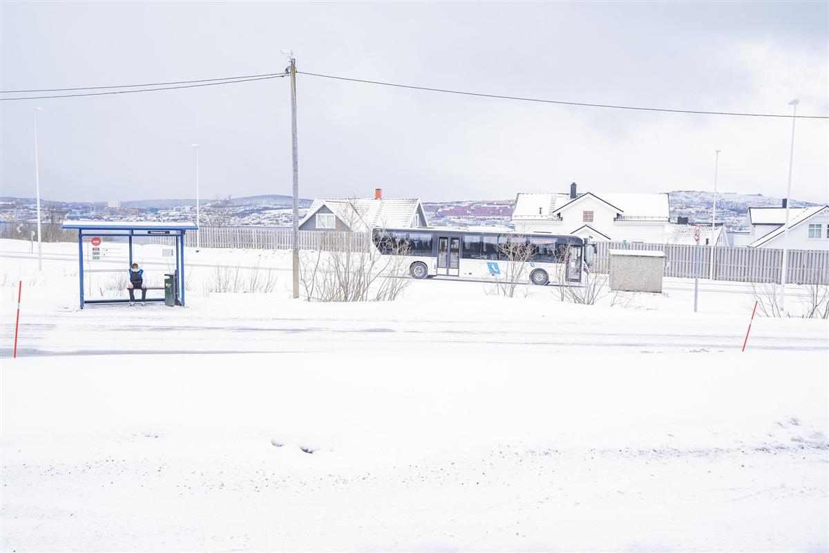 Bilde av en buss som kjører forbi en bussholdeplass. Det er masse snø på bakken, og fint klart vær.  - Klikk for stort bilde