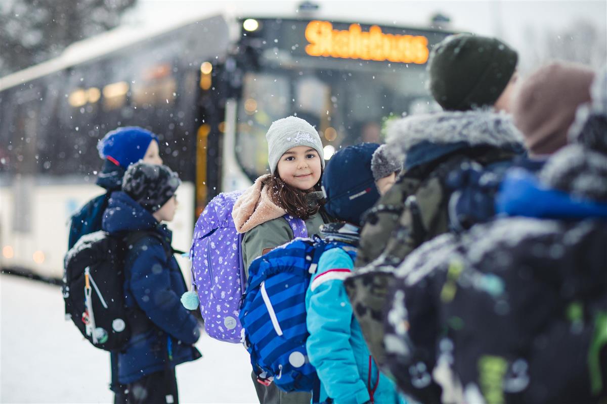 Bilde av skolebarn som skal ta skolebussen til skolen. Det er snøvær. Foto. - Klikk for stort bilde